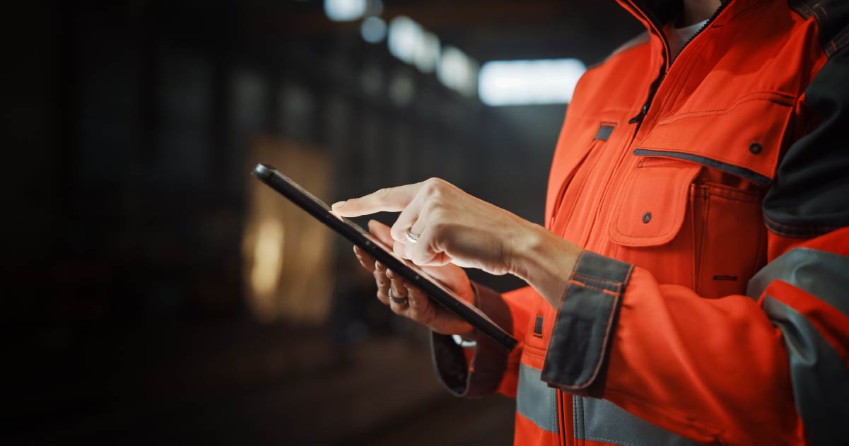 Person in an orange reflective construction jacket using a tablet to estimate