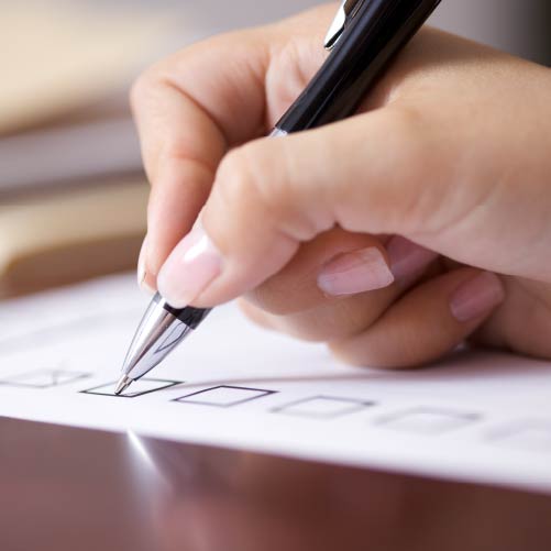 A hand holding a pen about to tick a checkbox on a piece of paper