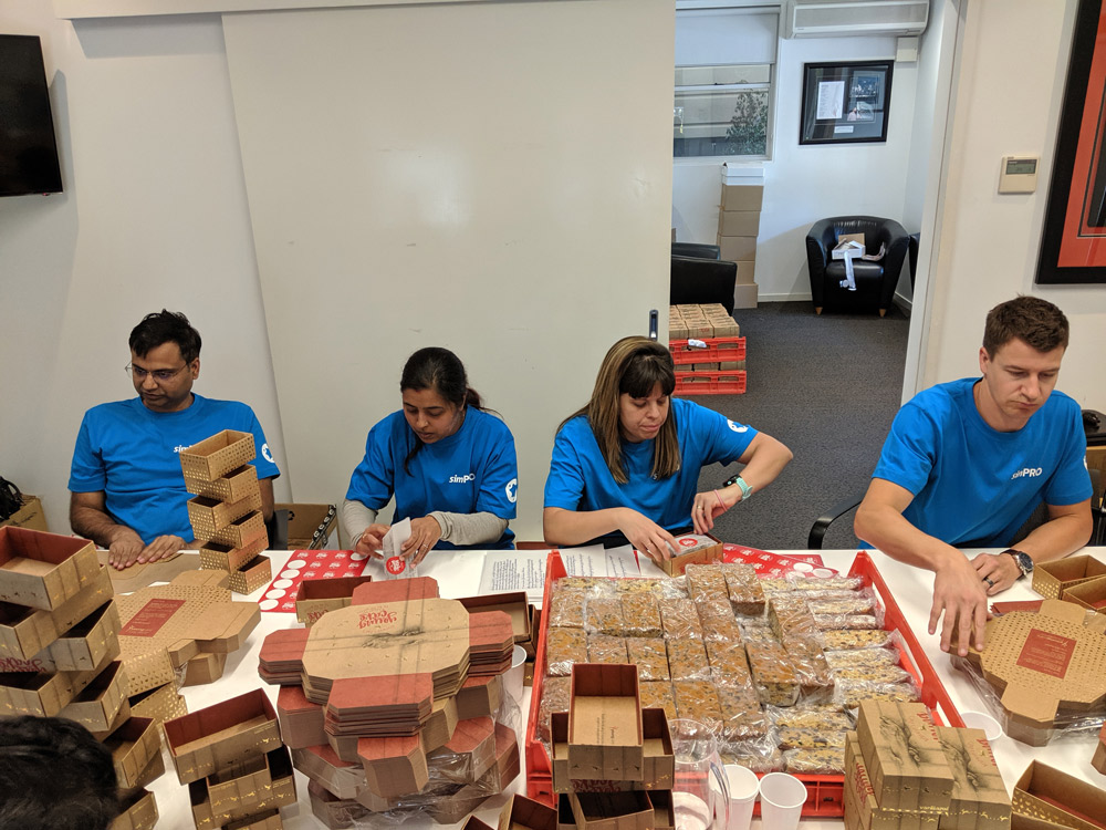 Simpro employees wrapping and packaging cakes