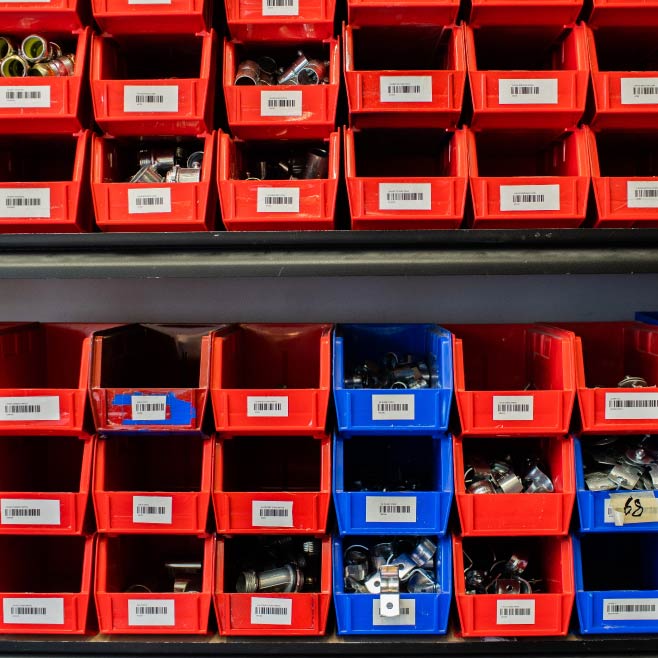 Rows of small red and blue storage boxes each with different parts inside.